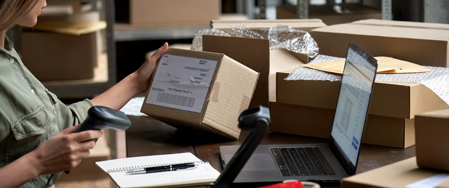 Person scanning shipping packages at desk